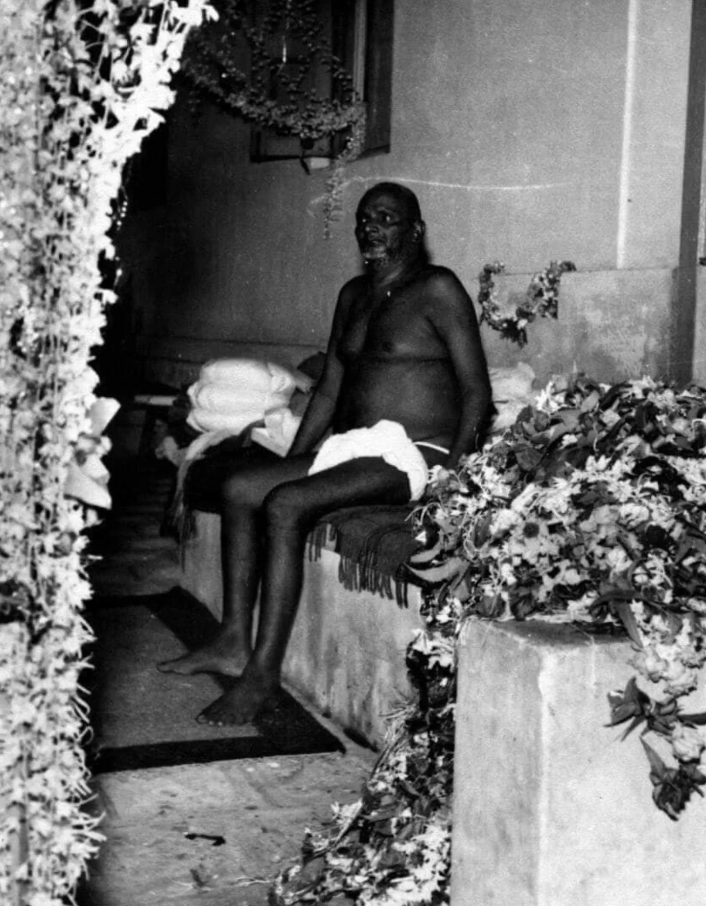 Bhagawān Nityānanda seated among flower garlands