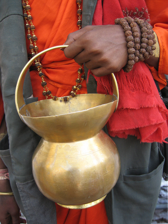 A sadhu holding a brass kamaṇḍalu