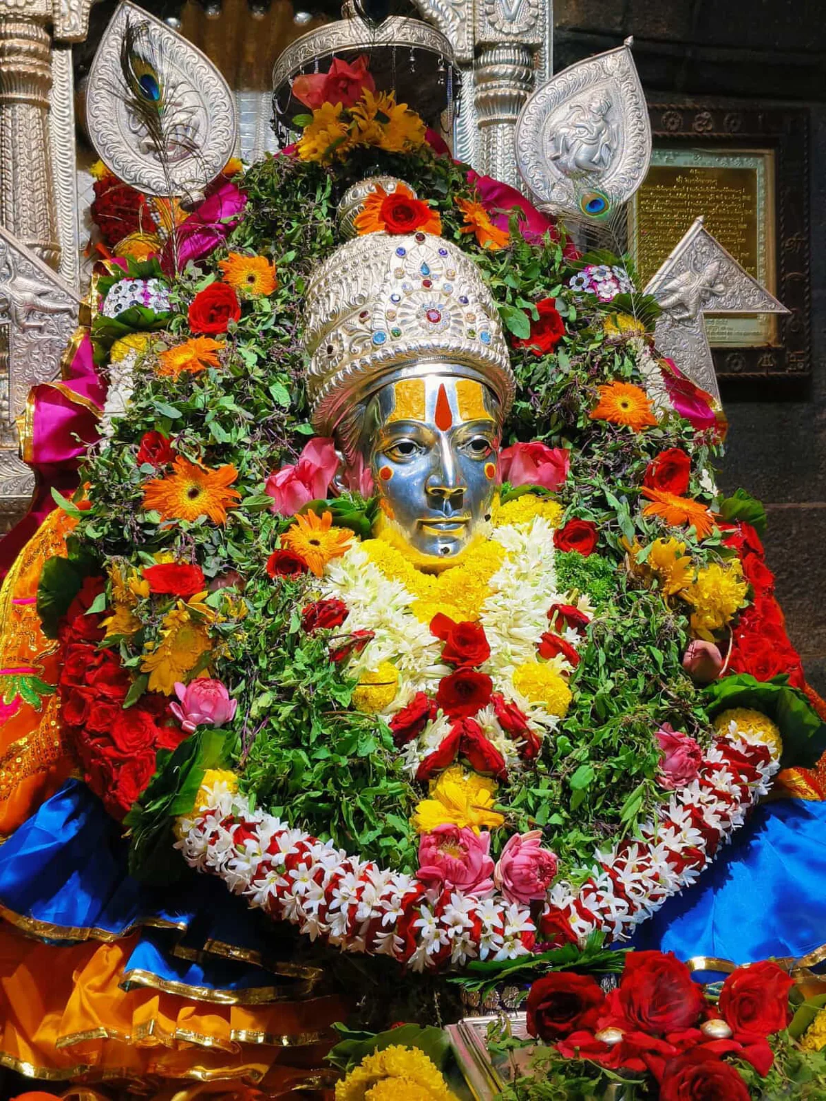 A flower-covered shrine with a silver-faced deity