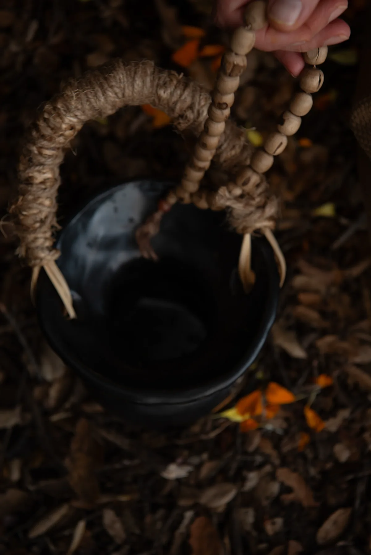 A hand holding prayer beads over a dark bowl